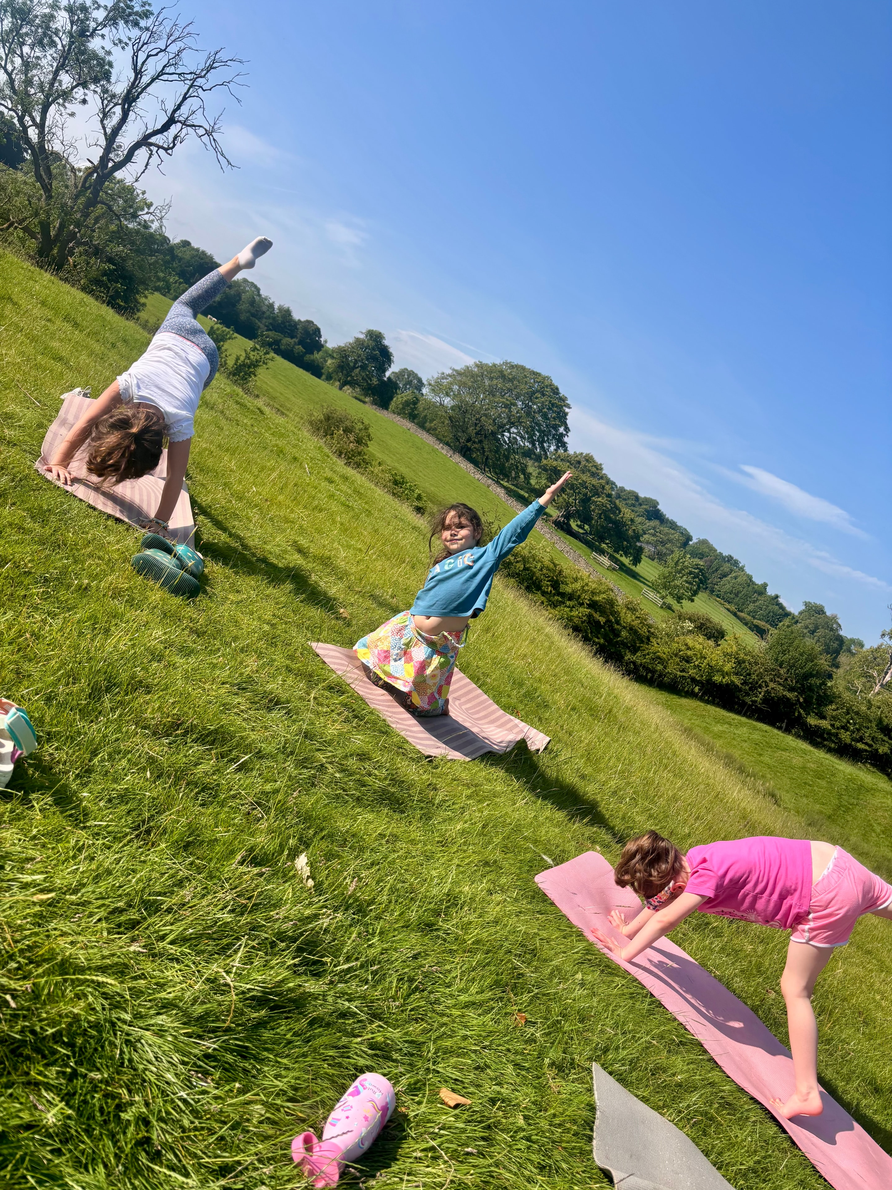 Children doing yoga outdoors on a sunny Ribble Valley hillside